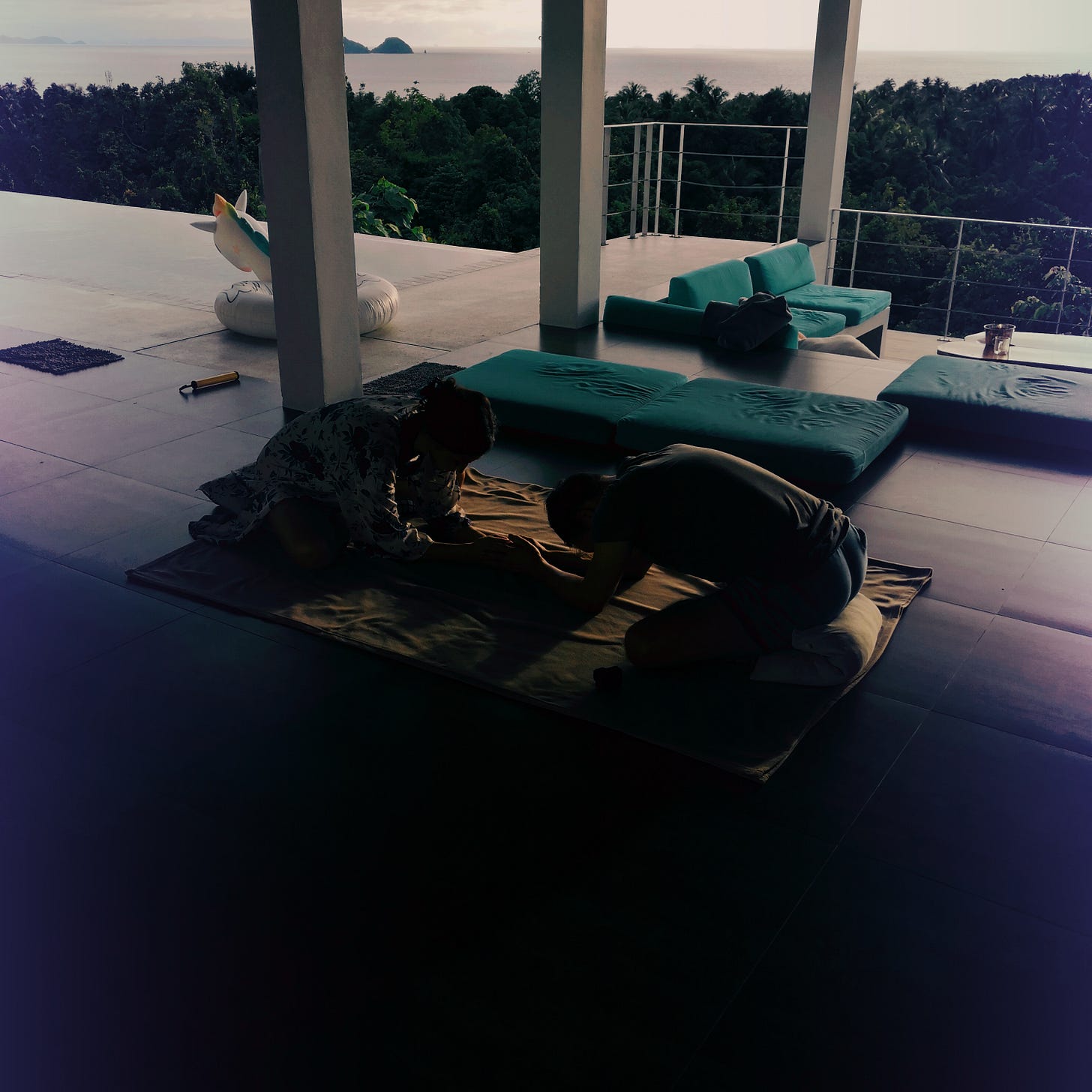 Two people bowing in tropical ocean yoga practice during Thailand retreat